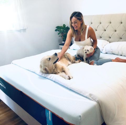 Clare Crawley in a white top poses with her two pet dogs.